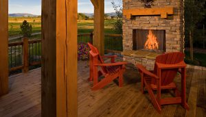 black bull club porch with lit fireplace and red wooden chairs with mountains and grass in background