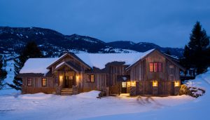 luxury log home at night in winter with lights on