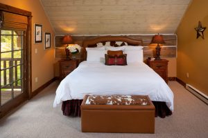 summer cabin residence bedroom with plush bedding and wooden accent wall
