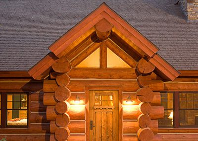 log cabin construction in Big Sky, Montana close up of front door with lights on inside