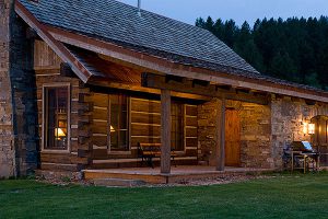log cabin construction Big Sky, Montana front door and deck with stone wall and square logs