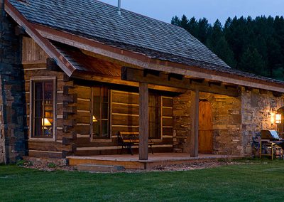 log cabin construction Big Sky, Montana front door and deck with stone wall and square logs