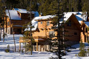 log cabin construction in Big Sky, Montana in snow with pine surrounding