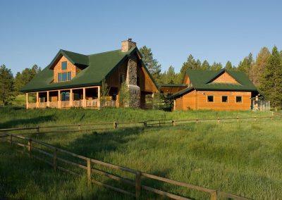 log home exposed beams exterior fenced lawn midday and back porch