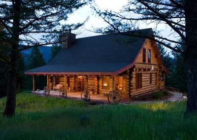 log home in forest during daytime with wagon wheels accenting the porch area