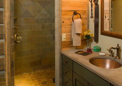 interior of a house modeled in the style of an old forest service cabin bathroom with stone countertop and shower