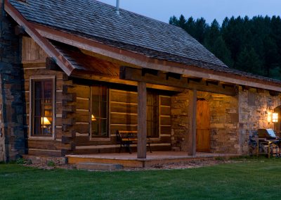 house modeled in the style of an old forest service cabin lawn and entrance at dusk