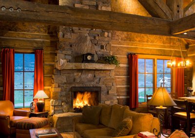 house modeled in the style of an old forest service cabin living room with roaring fireplace and sloped ceilings