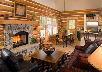 rmr group construction interiors living room and kitchen with stone fireplace and log walls